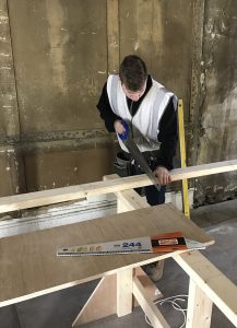 Carpentry apprentice sawing